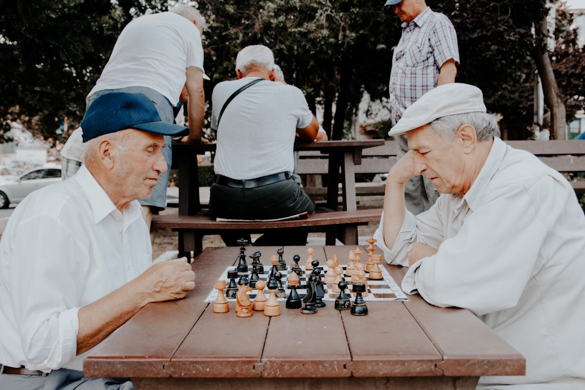 Two senior gentlemen engaging in a friendly game of chess, representing enrichment programs at VitalNest Living